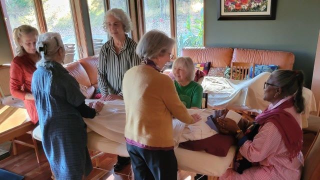 Women on table receiving reiki from fellow board members in a warm and cozy room with lots of natural sunlight