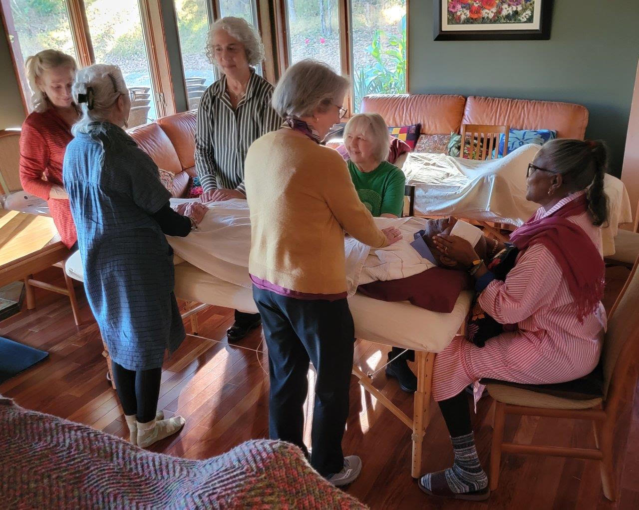 Women on table receiving reiki from fellow board members in a warm and cozy room with lots of natural sunlight